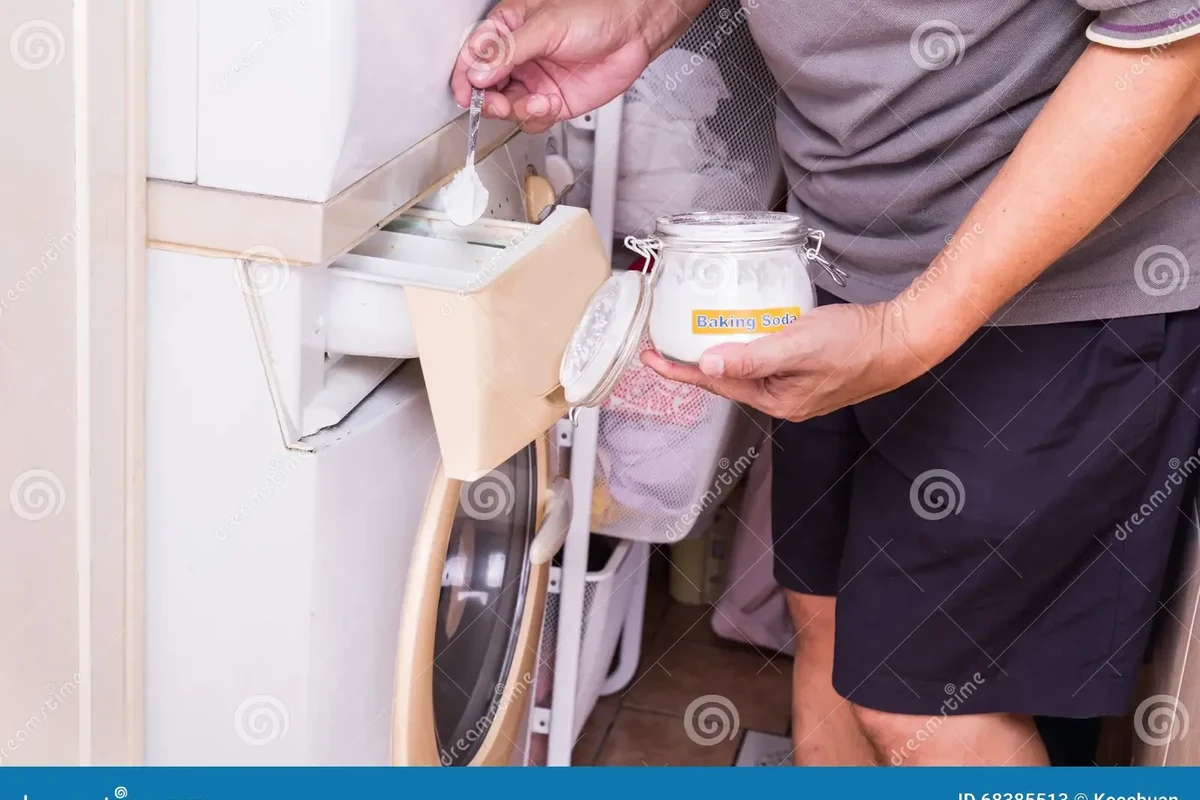 Laundry basket with baking soda, detergent, and fresh white towels on a washer