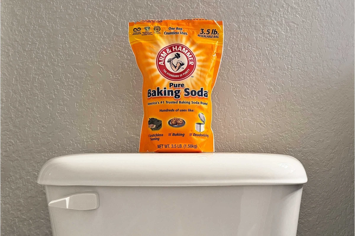 Baking soda being sprinkled into a toilet tank for gentle cleaning