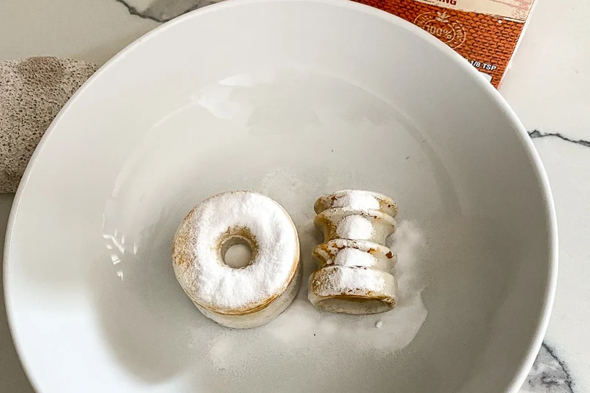 Baking soda paste being used to remove a rust stain from a sink