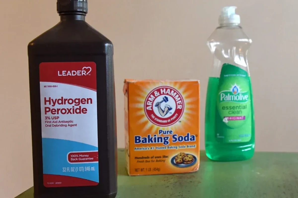 Baking soda sprinkled on fabric and cleaning supplies for skunk smell removal