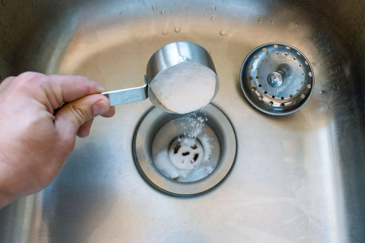Baking soda and vinegar fizzing in a kitchen sink drain to help with odor and buildup