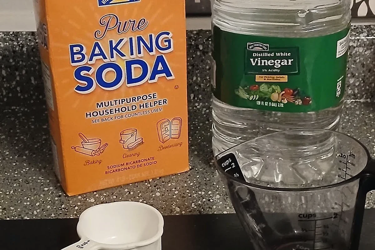 Baking soda and vinegar cleaning a kitchen drain to help reduce drain gnats