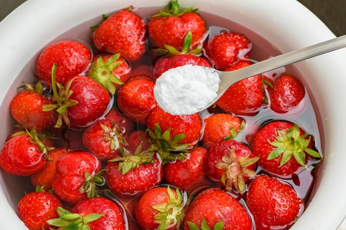 Fresh strawberries being washed in a bowl with baking soda and water