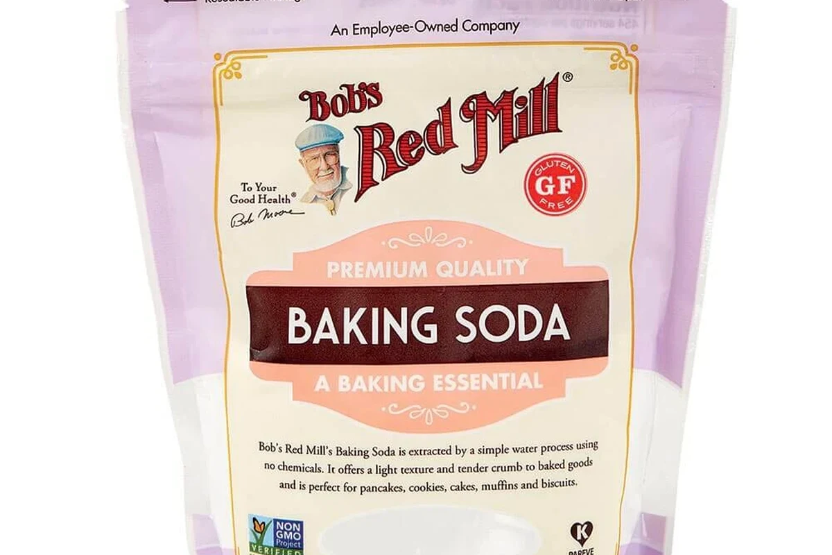 Baking soda container beside muffins, cookies, buttermilk, and measuring spoons in a bakery kitchen