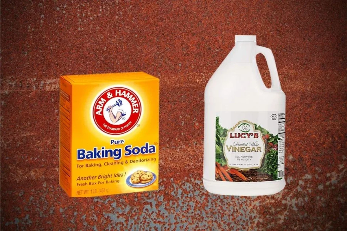 Hands cleaning light rust from a metal baking tray with baking soda and vinegar