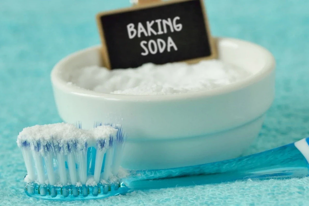 Person brushing teeth gently with baking soda paste in a bathroom