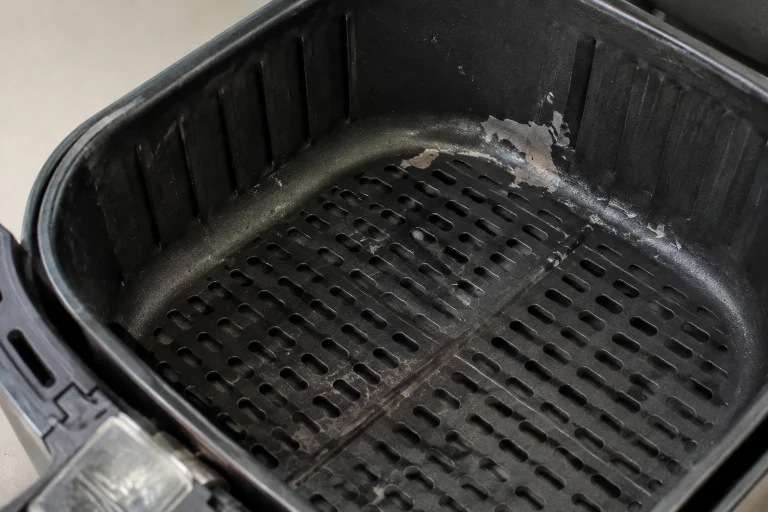 Close-up of an air fryer basket with peeling nonstick coating