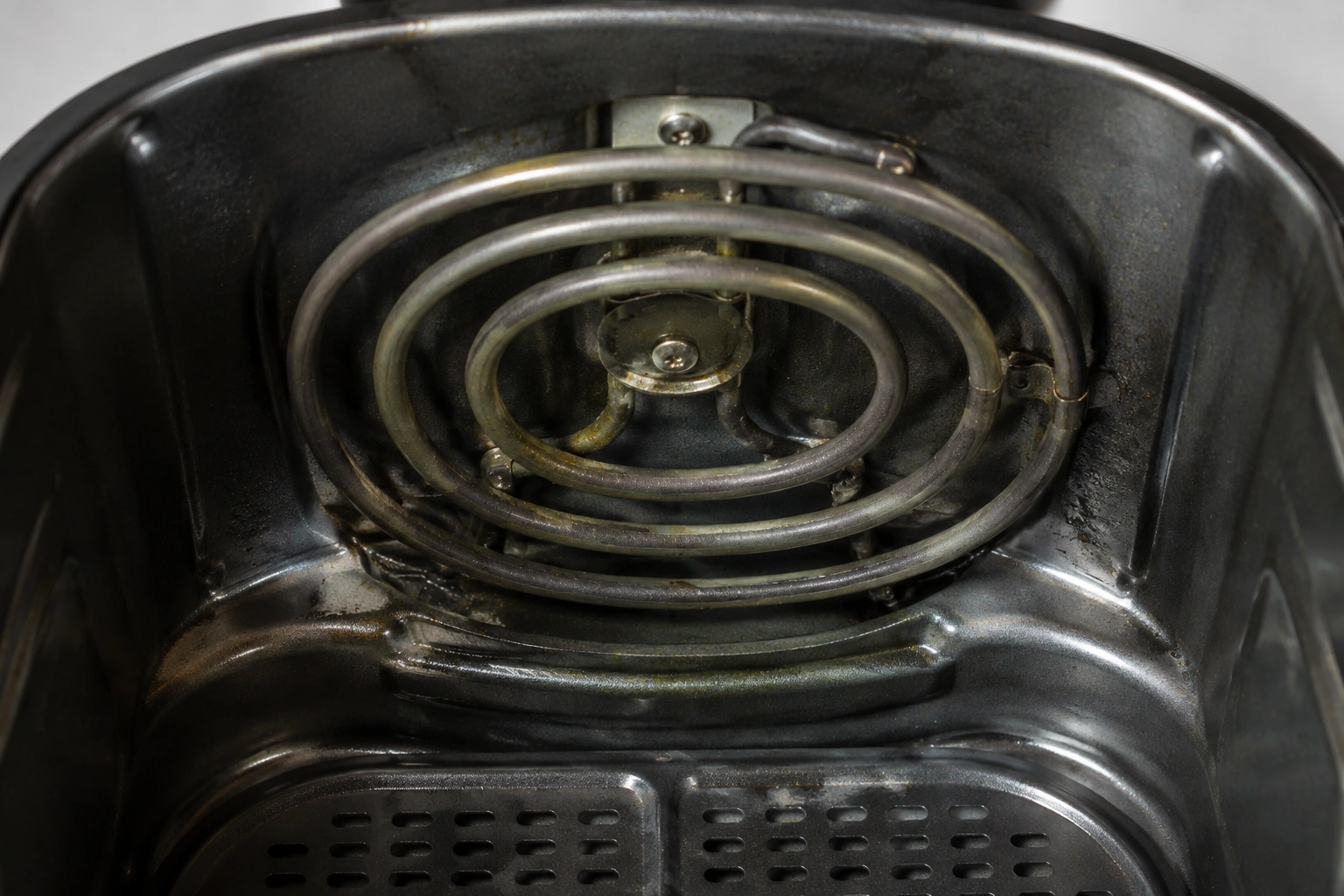 Close-up of an air fryer heating element with grease residue
