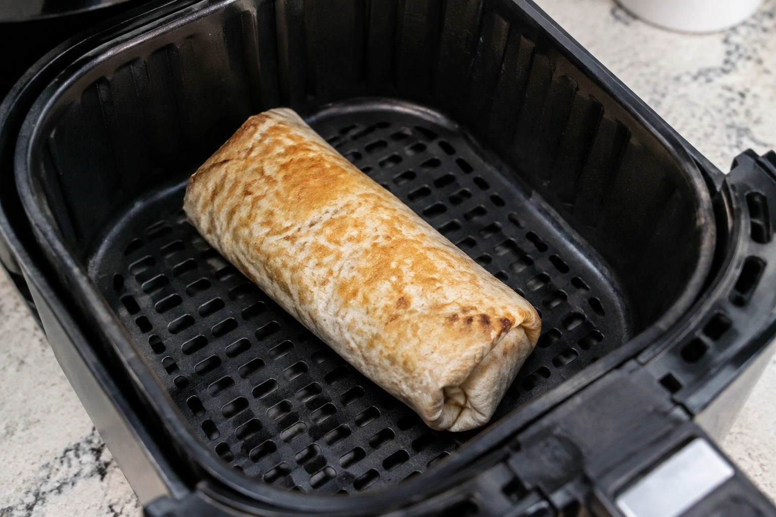 Frozen burrito heating evenly in an air fryer basket