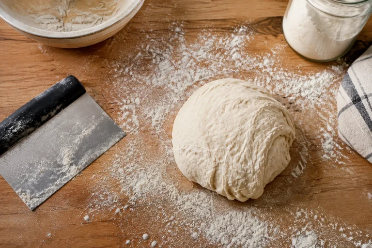 Bench scraper, lightly floured surface, and bread dough ready for pre-shaping
